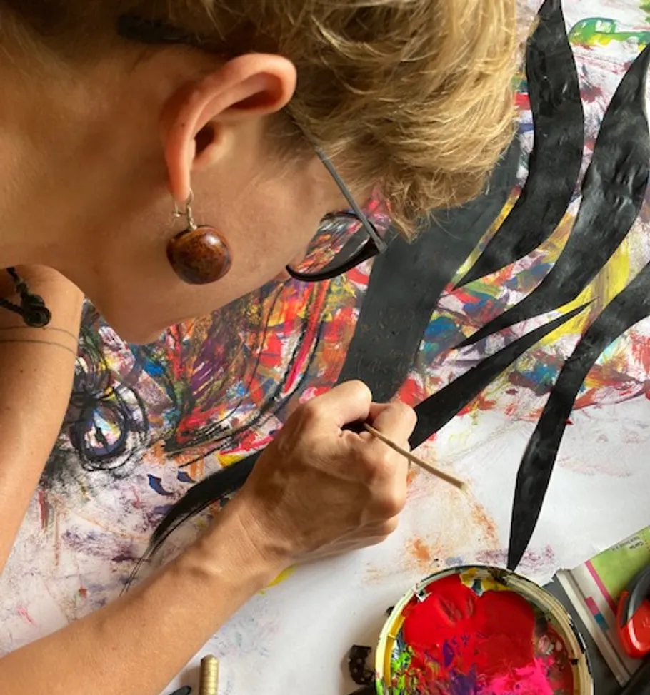 Artist paints with a brush on colorful paper.