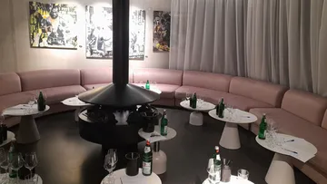 Round sitting area with table, drinks spread out on chairs.