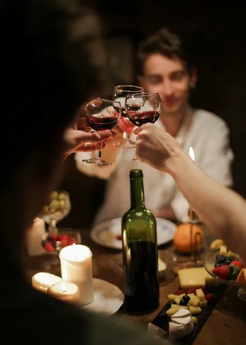 Glasses rise to toast in a cozy dinner context.