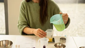 Messbecher wird mit einer Flüssigkeit in einen anderen gegossen, drinnen.