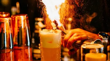 Brennendes Getränk wird von Barkeeper in einer Bar zubereitet.