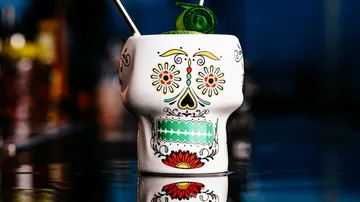 Colourful skull mug stands on a reflective surface