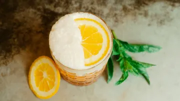 A glass of lemon liqueur and mint on a table.