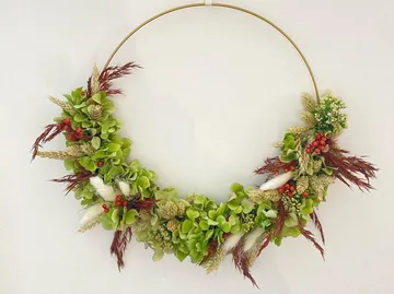 Circular wreath of green and red plants on the wall.