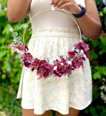 Flower ring held, surrounded by green nature.