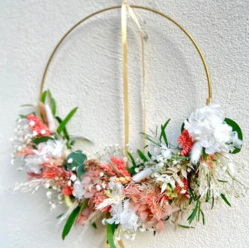 A hanging flower wreath adorns a wall with paints.