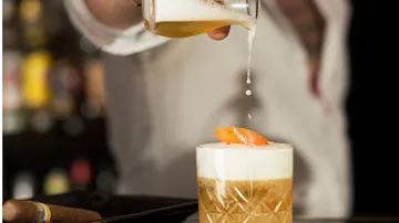 Ein Cocktailglas wird mit einer Flüssigkeit gefüllt.