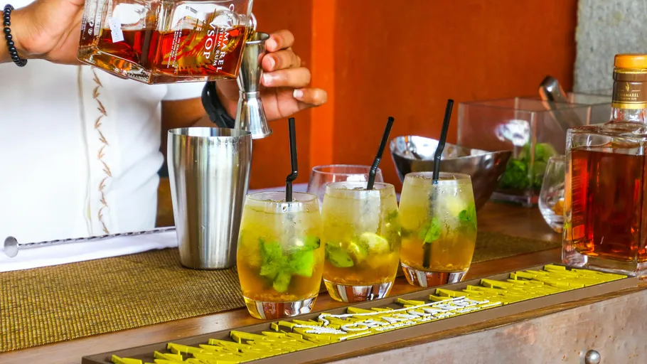 Bartender pours cocktails into glasses on the counter.