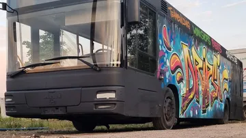 Bunter Bus mit Graffiti steht an einem leeren Ort.