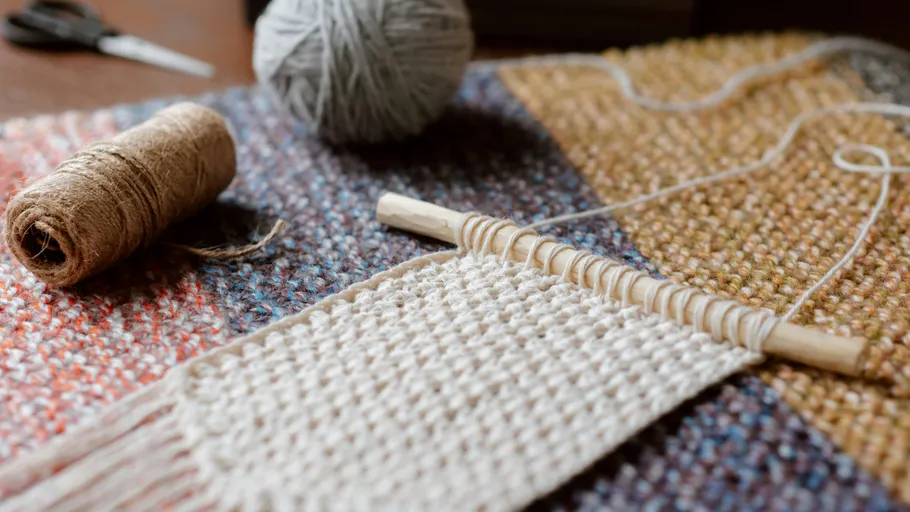 Woolen threads and weaving frames create a decorative piece of textile.