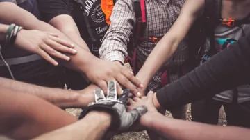 Several hands meet in the middle, symbolizing team spirit.