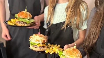 Hamburgers and fries are served by several people.