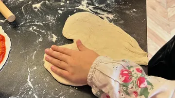 Teig wird mit einer Hand auf einer Arbeitsfläche bearbeitet.
