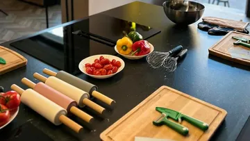 Kitchen table arranged with cooking utensils and fresh ingredients.