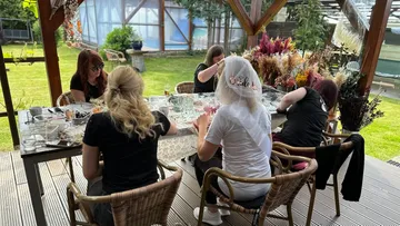 Gruppe von Frauen feiert im Freien um einen Tisch.