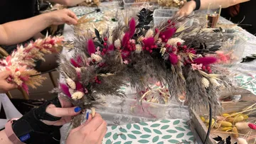 Haarreif wird mit Trockenblumen geschmückt, kreative Umgebung.