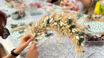 A person creates a wreath of hair from dried flowers.