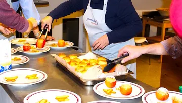 Chefs place prepared dishes on vegetable plates in the kitchen.