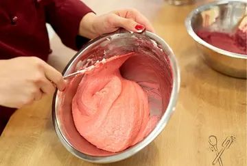 The person who cooks pink dough in a bowl.
