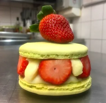 Green macaron with strawberries and cream placed in kitchen