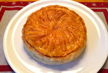 Runder, goldbrauner Kuchen liegt auf einem weißen Teller.