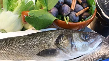 Fish lies next to fresh vegetables and fruits.