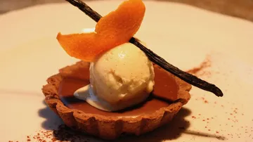 Schokoladentarte mit Vanilleeis und Orangenschale dekoriert.