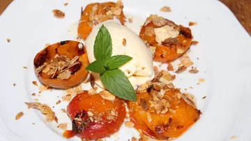 Grilled peaches with ice cream and broken nuts.