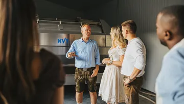 Mann erklärt Gruppe vor einer Maschine in geschlossener Umgebung.