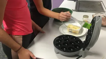 A child butters a waffle iron.