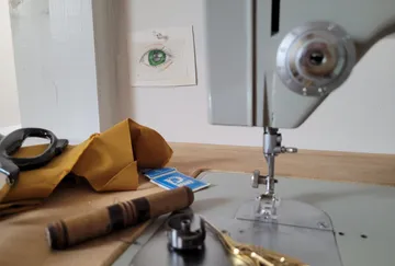 Sewing machine sews fabric on a table in a creative setting.