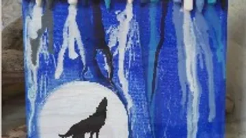 Schwarz-weißer Wolf vor einer großen, blauen Mondscheibe.