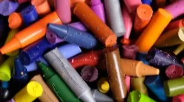 Bunte Wachsmalstifte liegen durcheinander auf einer Oberfläche.