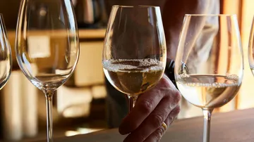 Wine glass in hand, sparkling drink in warm surroundings