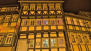 Timbered house with illuminated windows in a nocturnal setting.