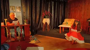 Actors read lyrics on a stage with decor.