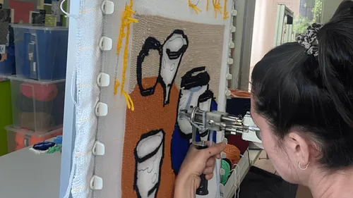 Frau benutzt eine Nadelmaschine zum Teppichknüpfen.