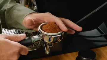 Coffee powder is filled into a portafilter, on an espresso machine.