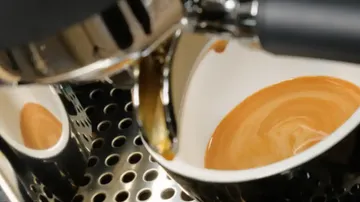 Coffee mug is filled with fresh espresso from the machine.