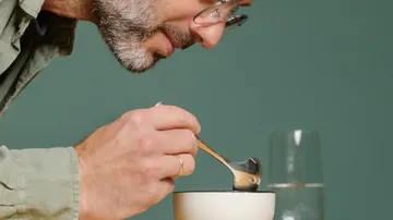 Mann löffelt aus einer Schüssel, umgeben von Wasser.