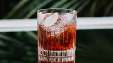 Ein Glas mit rotem Getränk steht auf einem Tisch.