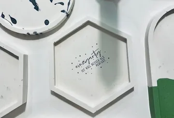 Sechseckige Platte zeigt inspirierenden Spruch auf weißem Hintergrund.