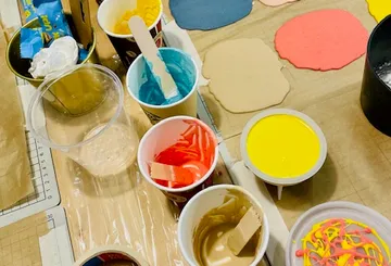 Bunte Farben in Behältern, die auf einem Tisch angeordnet sind.