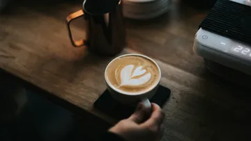 Cappuccino mit Latte Art auf einem Holztisch.