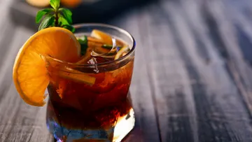 Ein Glas mit Getränk und Frucht, auf einem Holztisch.