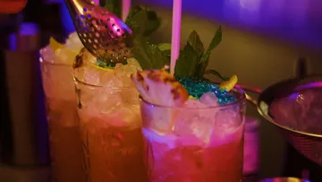 Cocktails with ice cream and decorations are prepared in a bar-like setting.