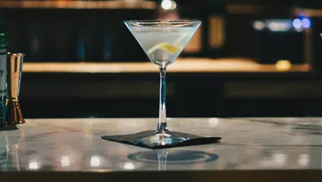 A cocktail glass is placed on a table with a napkin.