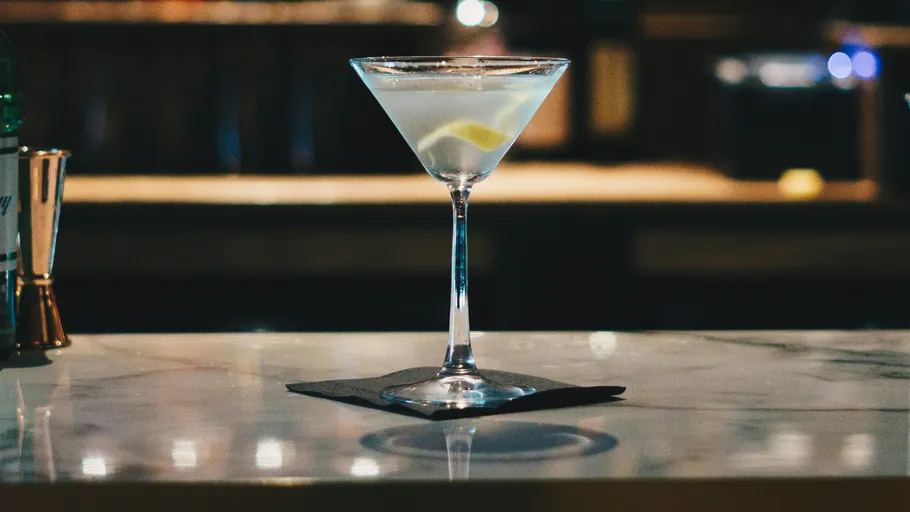 Ein Cocktailglas steht auf einem Tisch mit einer Serviette.