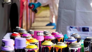 Sprühdosen stehen auf einem Tisch; Graffiti wird erstellt.