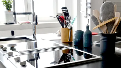 Kitchen surface with hobs and cooking utensils, modernly furnished.